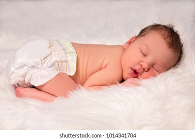 Cute Sleeping Newborn Baby In Diaper Over White Fur Blanket