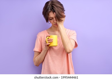 Cute sleepy woman having no enough sleep, holding yellow mug in hands, coffee in the morning. Adult woman need go at work or university. Isolated purple background
