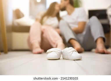 Cute Small babies shoes.Man hugs pregnant woman. Waiting for a baby birth. Happy family.