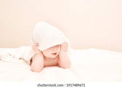 Cute small boy lying at bed. Childhood bath concept. Light background. Little child. Serious emotion. Copyspace. Stay home. Towel mockup. Hide from mom