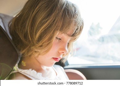 Cute Small Child, Blonde Girl, In Car Seat Wearing Seat Belts Happy Is Going To Go In The Path Of The Road, Sun Glare Reflected