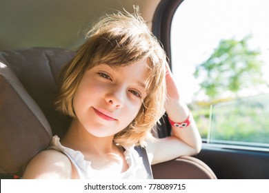 Cute Small Child, Blonde Girl, In Car Seat Wearing Seat Belts Happy Is Going To Go In The Path Of The Road, Sun Glare Reflected