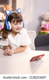 Cute Small Kid Girl Vlogger Talking To Camera At Home Recording Vlog For Social Media Blog, Video Conference Calling Virtual Friend Having Online Meeting Sitting In Chair.