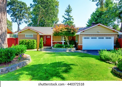 Cute Small Rambler House With Red Door And White Garage Door. Front Garden With Well Kept Lawn.