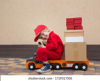 cute  smiling 4-year-old boy in red overalls and a cap sits on  big toy car -  truck with many cardboard boxes on it. Parcel delivery, small postman, small truck driver. Positive, joy, games for boys - Shutterstock ID 1729317505