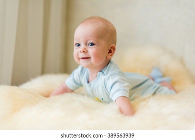 Lächelndes Baby, Klein glückliches lächelndes Kind liegt auf dem Magen auf weich geplaid