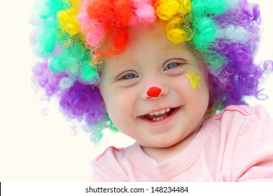 A cute, smiling baby boy is dressed up in a clown costume with colorful wig and clown make up face paint - Powered by Shutterstock