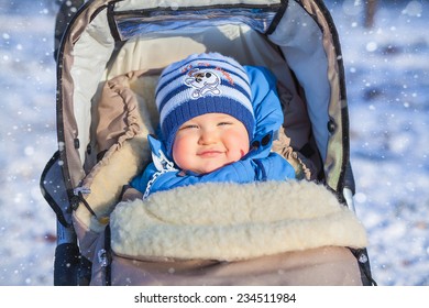 Cute Smiling Baby Sitting In A Stroller On A Cold Winter Day