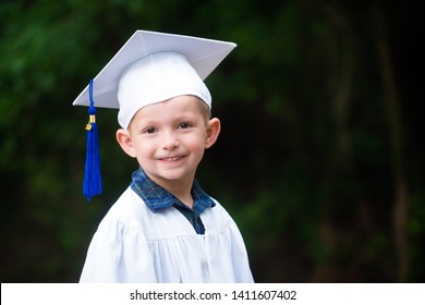Cute Smiling Boy In Cap And Gown After Kindergarten Graduation