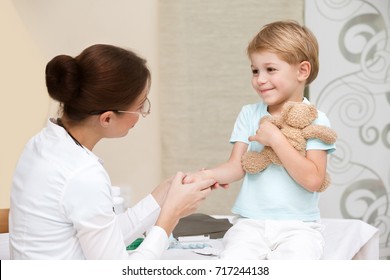 Cute Smiling Boy At The Doctor With His Little Toy Friend, Not Affraid To Visit Pediatrician, Happy Healthy Childhood