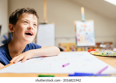 Cute smiling boy with down syndrome playing with paint at painting studio for special need children. - Powered by Shutterstock