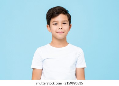 Cute smiling boy in plain white t shirt looking at camera in isolated studio light blue color background - Shutterstock ID 2159990535