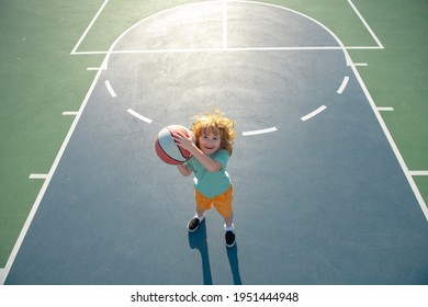 Cute Smiling Boy Plays Basketball. Kid Shooting Basketball Ball And Playing Basketball. Healthy Children Lifestyle, Outdoor On Playground