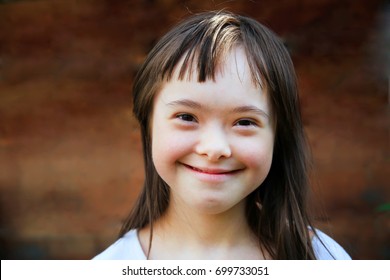 Cute smiling down syndrome girl on the brown background - Shutterstock ID 699733051