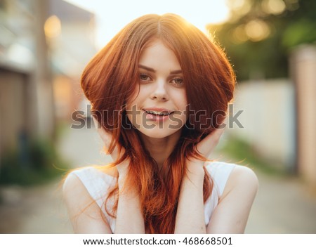 
cute smiling girl looking at you with hair flying in the sunset