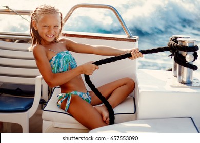 Cute smiling little girl enjoying on the deck. They are on cruise and sunbathing.