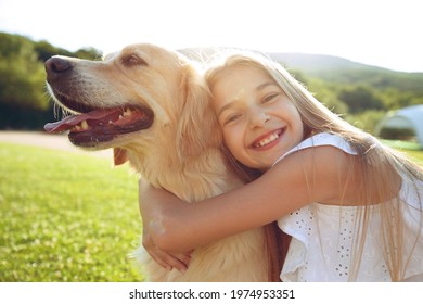 Cute smiling little girl hugs a retriever in a summer park. High quality photo - Powered by Shutterstock