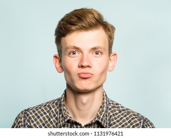 Cute Smiling Man Poting. Joyful Playful Behavior. Portrait Of A Young Guy On Light Background. Emotion Facial Expression. Feelings And People Reaction.