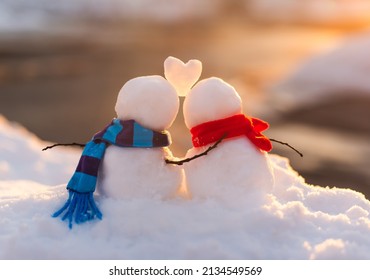 Cute snowman couple in love with snow heart between them.