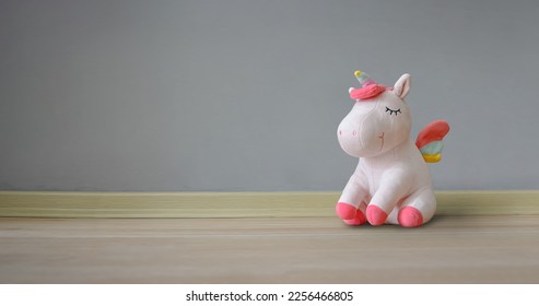 Cute soft unicorn plush toy on the floor. Close up shot, empty space