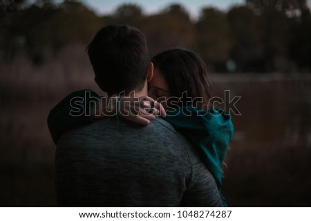 A cute spanish couple having a nice afternoon hugging and kissing each other in a park in front of a lake in Seville, Spain.