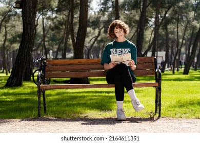 Cute Sportive Woman Wearing Tee Standing On City Park, Outdoors Sitting On Park Bench And Reading A Book. Self Improvement Concepts.