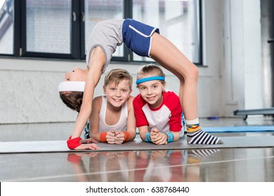 Cute Sporty Kids Exercising In Gym And Smiling At Camera, Children Sport School Concept