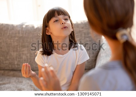 Cute stuttering child girl speaking doing exercises with speech therapist