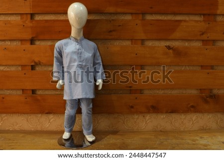 cute stylish kurta shalwar for kids on dummy on wooden background