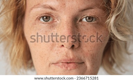 Cute sun kissed 30s woman look camera. Freckled girl face portrait. Irish young adult person. One 40s years old lady head shot. German skin care cream. Serious blond hair style. No make up life close.