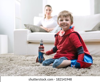 Cute superhero boy paying with toy rocket in the living room with his mother on background. - Powered by Shutterstock