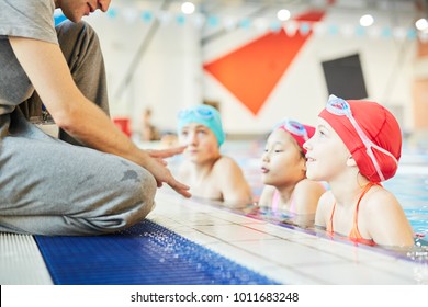 Cute swimmer and her groupmates in water listening to trainer instructions during training - Powered by Shutterstock