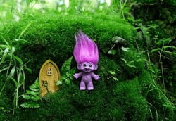 Cute Tale Troll And Little Wooden Door In Mystery Forest, Natural Abstract Background. Funny Troll Toy With Ruffled Violet Hair. Fairytale Beautiful Magic Atmosphere. Template For Design