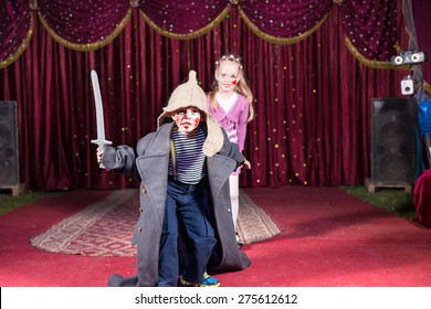 Cute talented boy playing the role of a brave Russian warrior fighting with a sward to defense his beautiful wife, in a theatrical performance at school