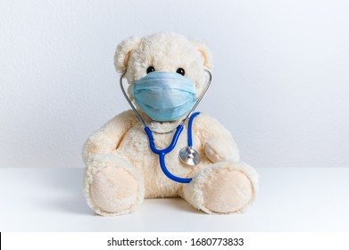 Cute teddy bear doctor with protective medical mask and stethoscope. Concept of pediatric treatment of illness, hygiene, epidemic and virus protection for child patient. Fluffy toy on white background