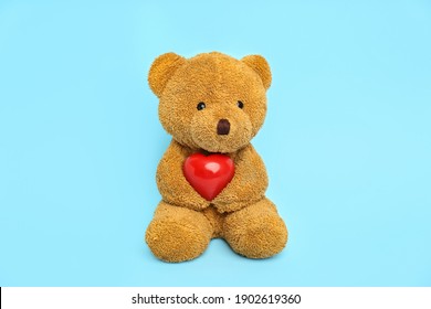 Cute teddy bear with red heart on light blue background. Valentine's day celebration