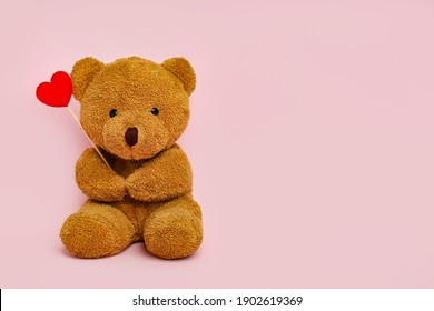 Cute teddy bear with red heart on pink background, space for text. Valentine's day celebration
