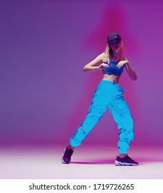 Cute Teen Girl Dancing Hip Hop In Reflective Pants, Baseball Cap, In A Studio With Neon Lighting. Dance Color Poster.