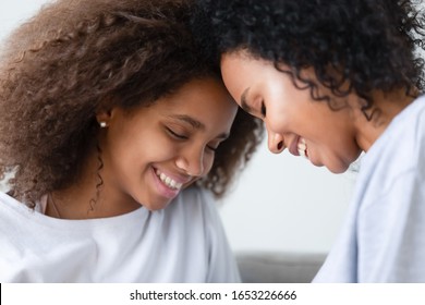 Cute teen girl and happy african american mom touching foreheads enjoy tender moments of love together, smiling black mother and mixed race teenager daughter having fun bonding, family love affection
