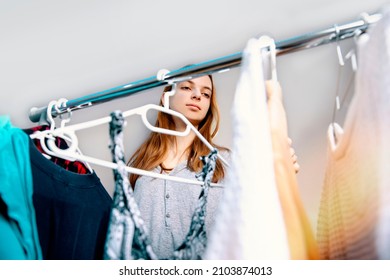 Cute Teen Girl In Her Bedroom Choosing What To Wear For A Night Out. Pretty Teenager Trying Different Outfits