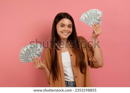 Cute Teen Girl Holding Dollar Cash In Two Hands And Smiling At Camera, Happy Female Teenager Showing Money Banknotes, Enjoying Savings And Economy While Standing On Pink Background, Copy Space