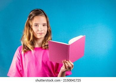 Cute Teen Girl In Pink Is Reading A Book. The Concept Of School, Education, Self-study, Reading Books, Poetry And Creativity, Keeping A Diary, Romance Novels, Traditional Values.