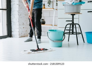 cute teenage boy do household chores, men housework, household help in stylish kitchen in modern apartment, doing laundry and mopping floors, mom's housemate, little helper - Shutterstock ID 2181309123