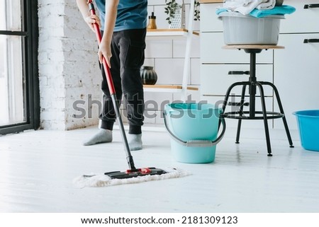 cute teenage boy do household chores, men housework, household help in stylish kitchen in modern apartment, doing laundry and mopping floors, mom's housemate, little helper
