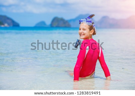 Cute teenage girl in bikini carrying scubadiving equipment