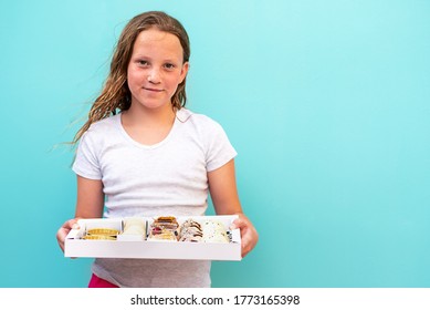 Cute teenage girl with freckles delivering to home the diverse sweets in a white box. Soft focus.
