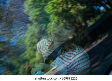 Cute teenage girl with teddy bear sleeping in the back seat of car - Powered by Shutterstock