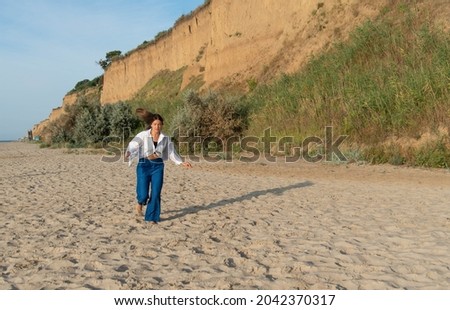 Cute teenage girl or woman wearing blue pants, white shirt, white bandana on the beach nature landscape fresh air beach. Natural beauty. lifestyle, real people, funny, dance.