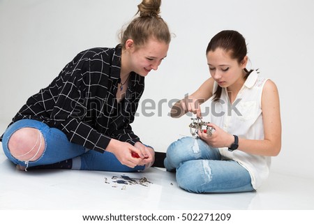 Cute teenage girls sitting on the floor mounting a little metal model