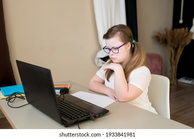 Cute Teenager Girl With Down Syndrome Learning Online At Home. Distance Learning By Video Call On Laptop. E-learning And Online Education For Kids With Special Needs Concept